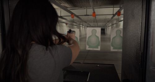 Krystal Dunn aiming a pistol at a target in an indoor range