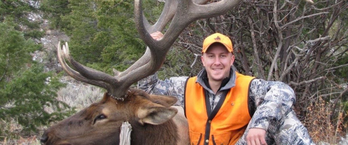 Hunter sitting in front of dead bull elk