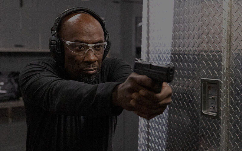 shooter aiming pistol at an indoor range