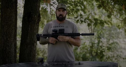 Josh Froelich holding a rifle outside