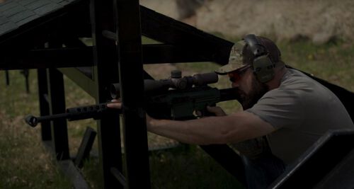 Josh Froelich aiming a rifle at an outdoor range