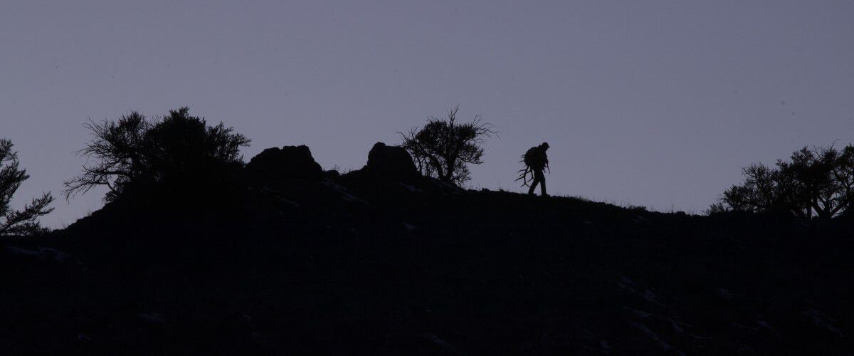 silohette of a man walking on a hill