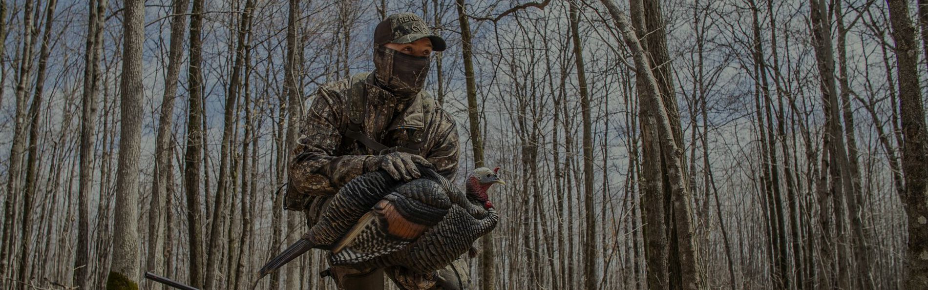 hunter squatting down with holding a shotgun