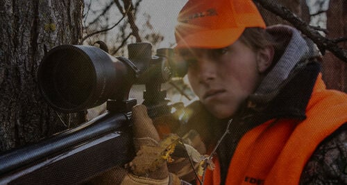 Lady shooting a rifle outside