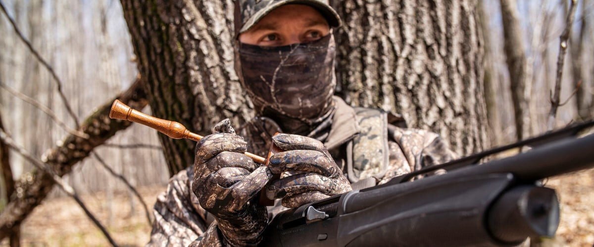 hunter using a turkey call in the woods