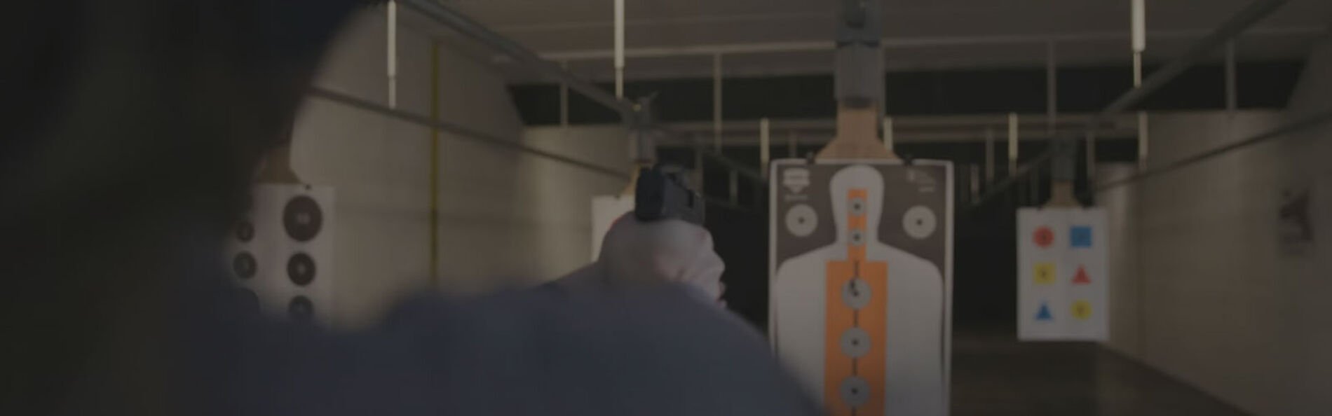 shooter aiming handgun at a target in an indoor range