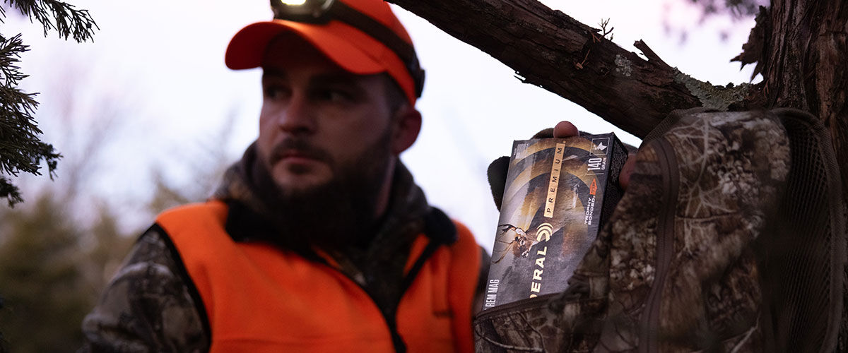 hunter grabbing box of Trophy Bonded Tip out of a backpack 