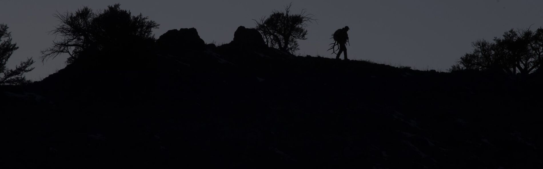 silohette of a man walking on a hill