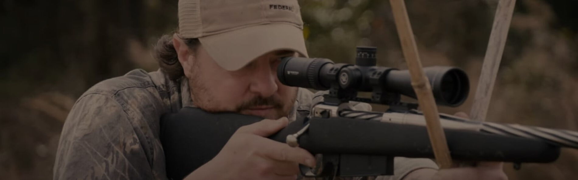 Jim Gilliland using a stickes and aiming his rifle