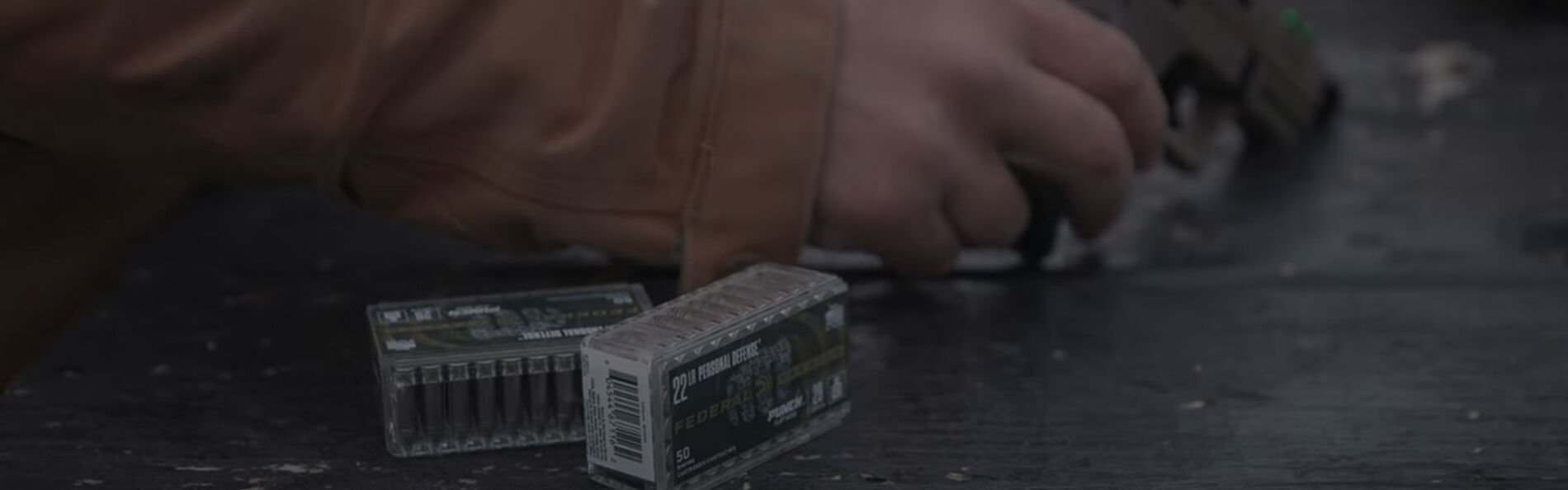 Josh Froelich grabbing the 22LR X Walther P22 off a table with two boxes of Punch ammo