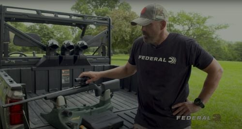 Lee standing by an ATV with a rifle in the back