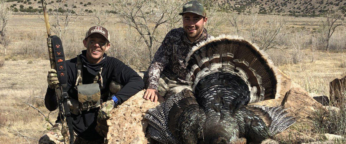 Two hunters kneeling beside a downed turkey