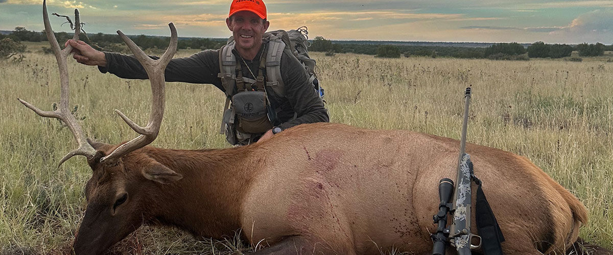 hunter standing behind a large elk buck