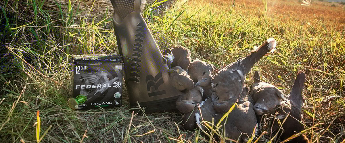 pile of doves and Upland Steel paper wad box and shotgun in the grass