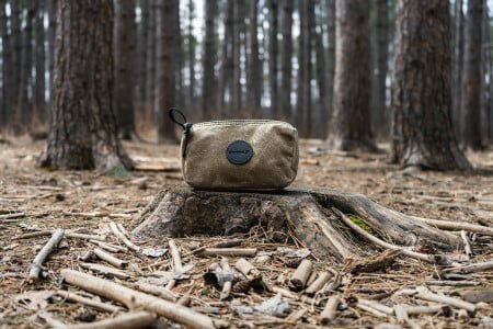 Khaki Grab-N-Go Bag sitting on a tree stump in a wooded area
