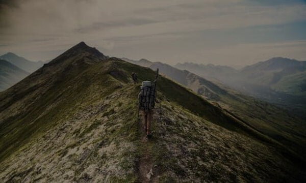 hunter walking on the top of a mountain with mountains all around