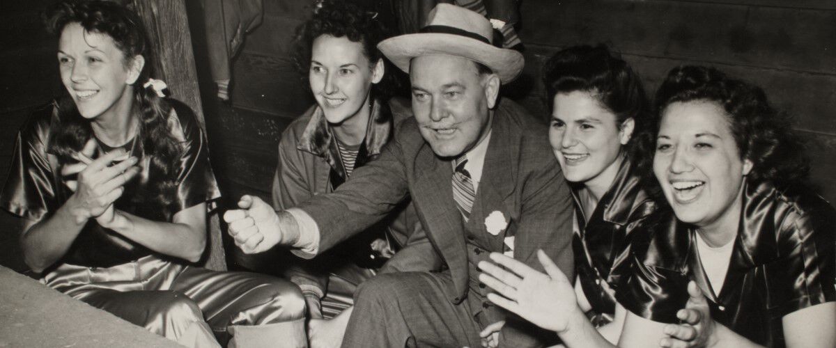 Charles Horn sitting with some female softball players in the dugout