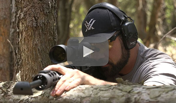 Josh Froelich kneeling behind a large fallen tree trunk
