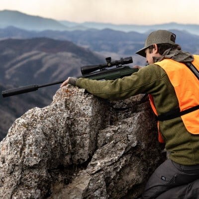 Adult helping child shoot a rifle