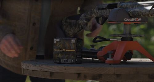 A shotgun on a table outside next to Federa Black Cloud