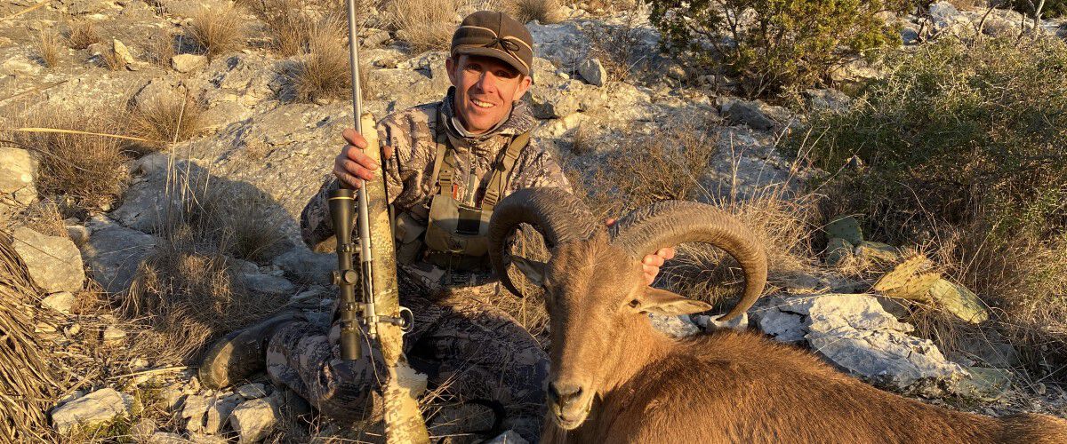 Jace Bauserman sitting beside dead mountain goat