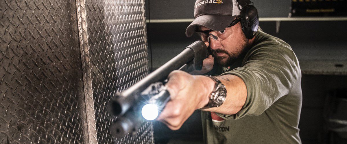 man shooting shotgun at an indoor range