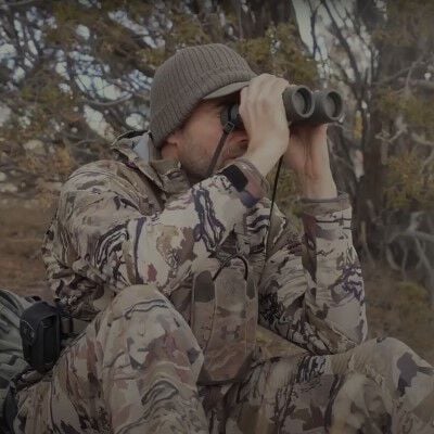 Remi Warren looking through binoculars when sitting on a hill need to a range finder