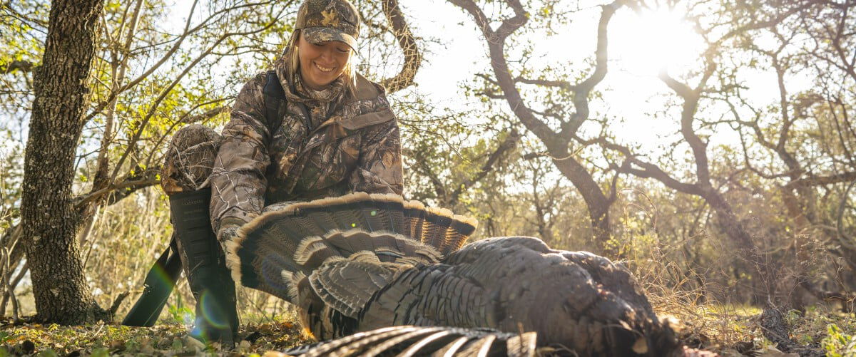 hunter standing behind a dead turkey on the ground
