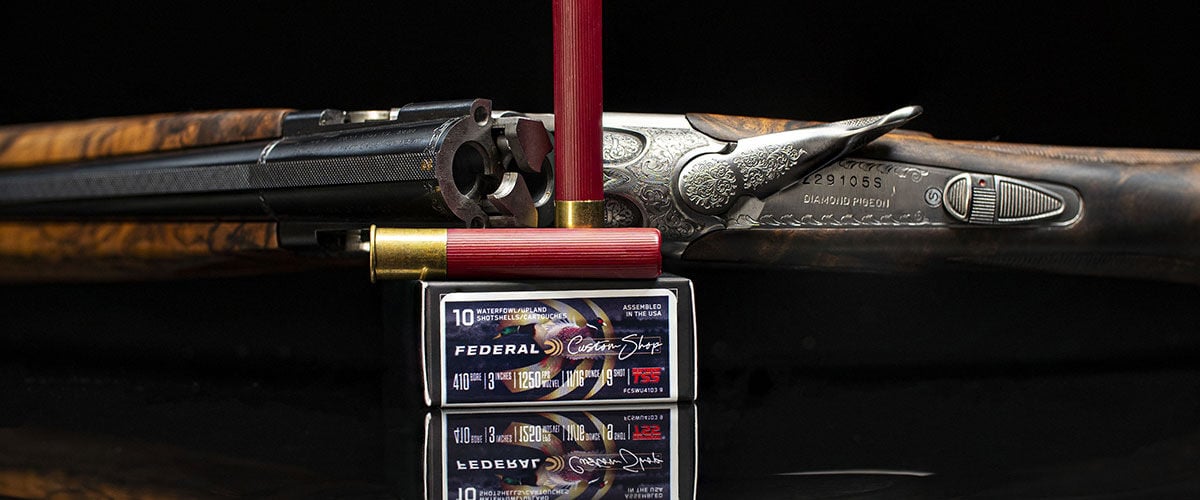 Custom Shop Shotshell sitting on top of the box with a shotgun behind